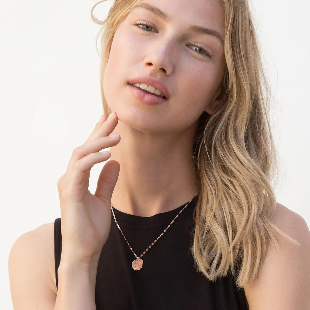 Round coin stainless steel pendant necklace in gold with adjustable side chain on a white background