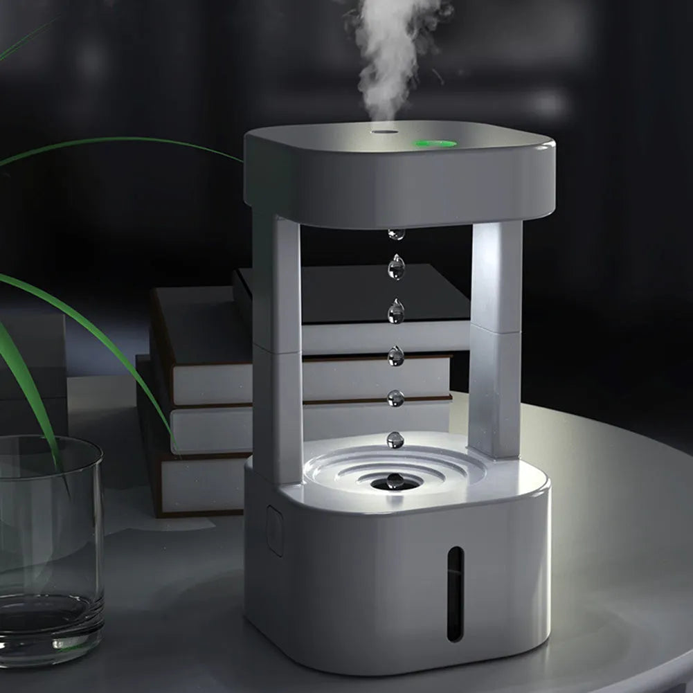 White anti-gravity water drop humidifier with coloured light on a desk next to USB cable