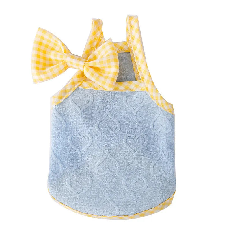 Small dog wearing a blue vest with a heart texture and back bow suspenders.