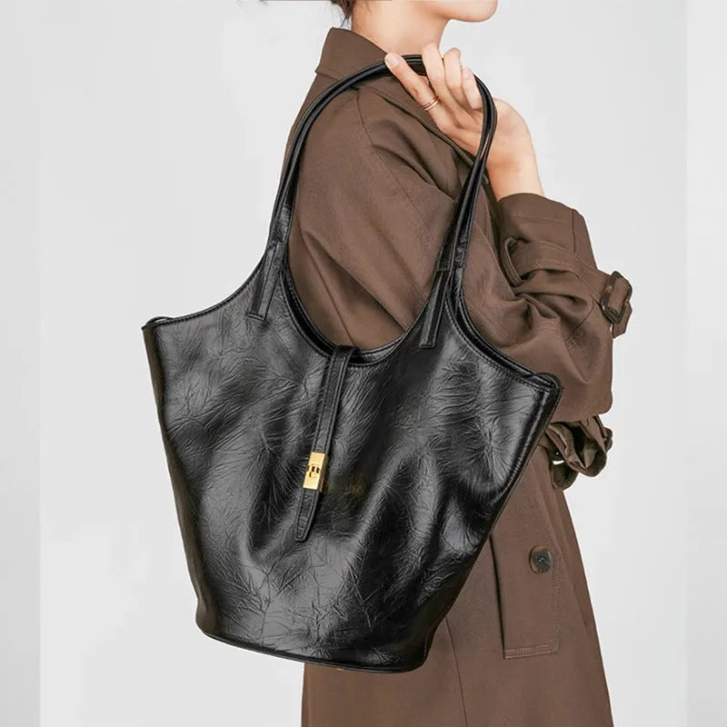 Black genuine leather large capacity bucket bag with visible stitching and crossbody strap on white background