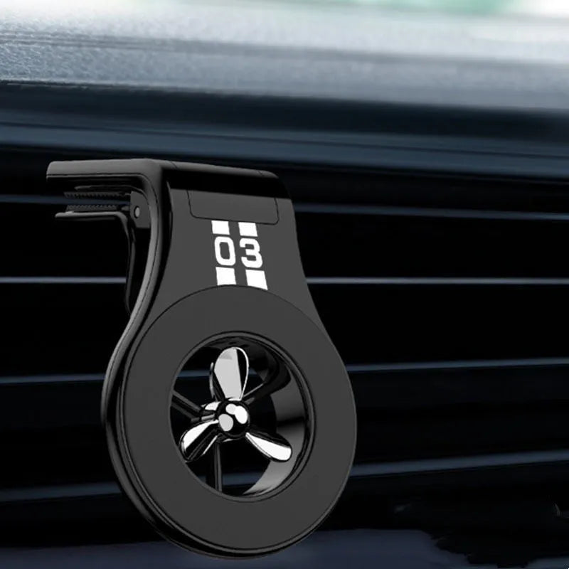 Black magnetic car phone holder mounted on a car air vent, showing 360-degree rotation and fragrance slot.