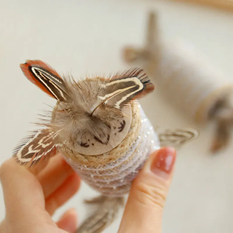 Beige cat toy with real feathers attached to hemp rope scratching surface and integrated claw roller