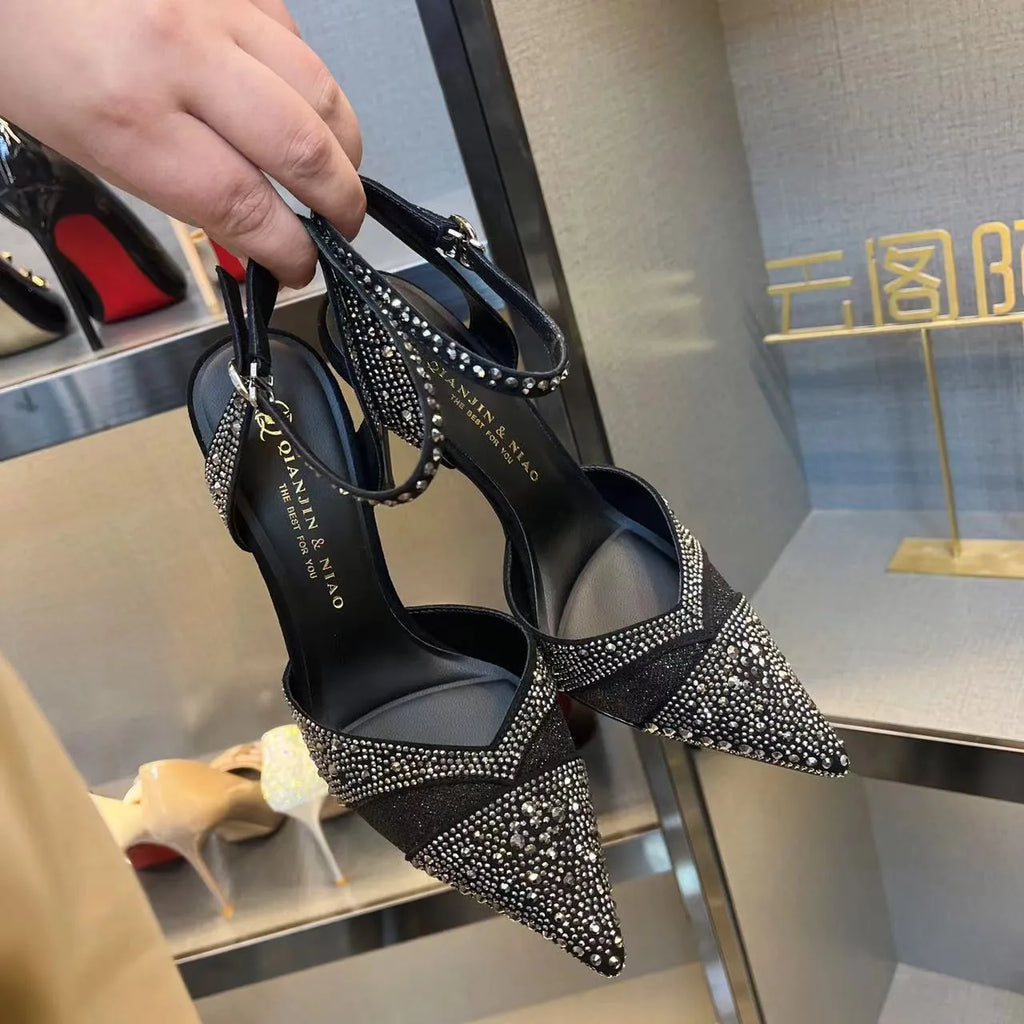 Women's black pointed-toe stiletto heels with a hollow-out design and red sole.