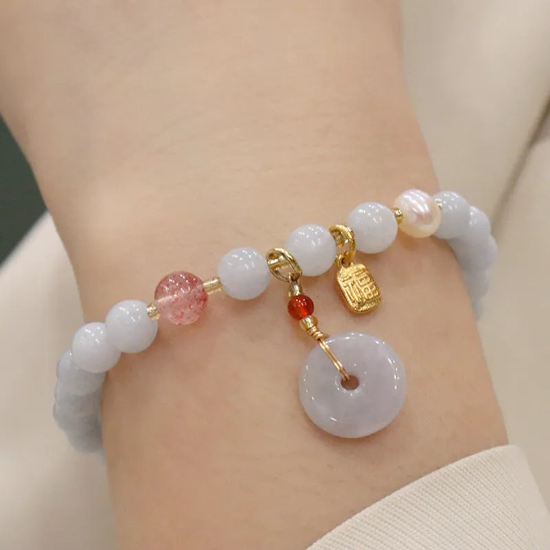 Gold plated bracelet with a detailed artificial crystal charm pendant on a woman's wrist.