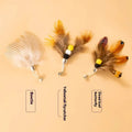 Three small steel-wire insect toy heads for cats in assorted colours, against a white background.