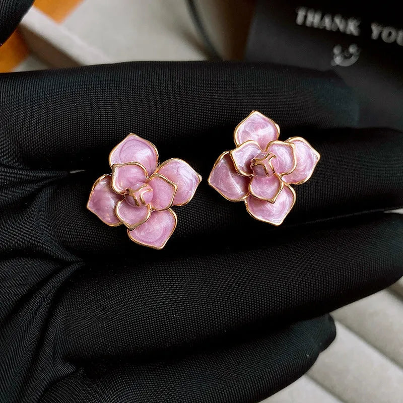 Gold plated purple oil-spot glaze flower stud earrings on a white background, showing detailed petal design and matte finish.