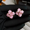 Gold plated purple oil-spot glaze flower stud earrings on a white background, showing detailed petal design and matte finish.