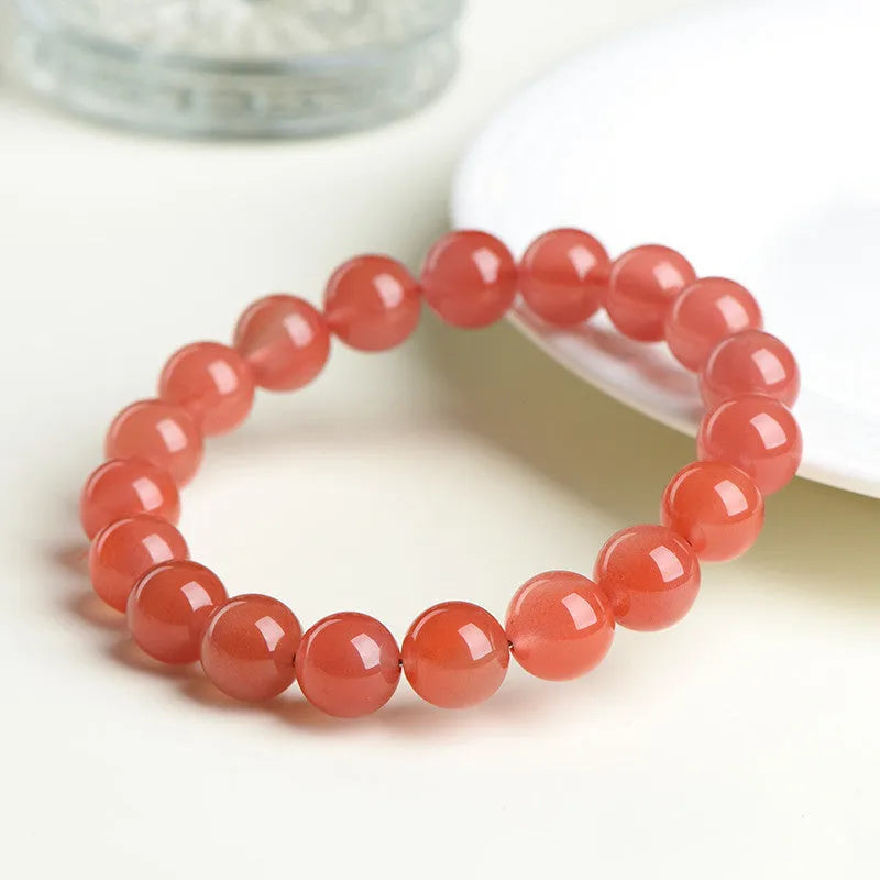 Natural cherry red agate bead bracelet with polished stones on a neutral background, showing single strand and bead detail.
