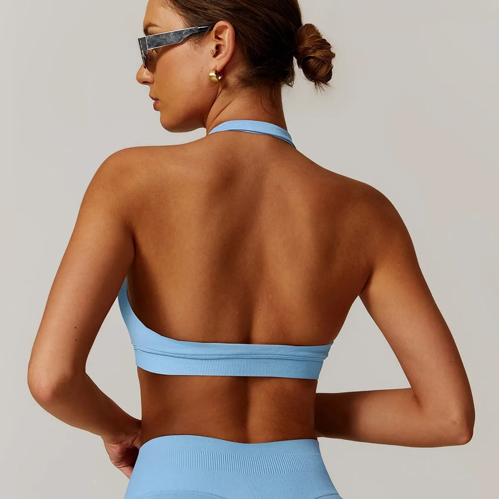 Women's black halter-neck sports bra with removable padding on a grey background.