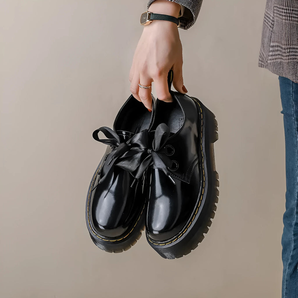 Black women's thick-soled lace-up shoes with decorative white ribbon cross straps.