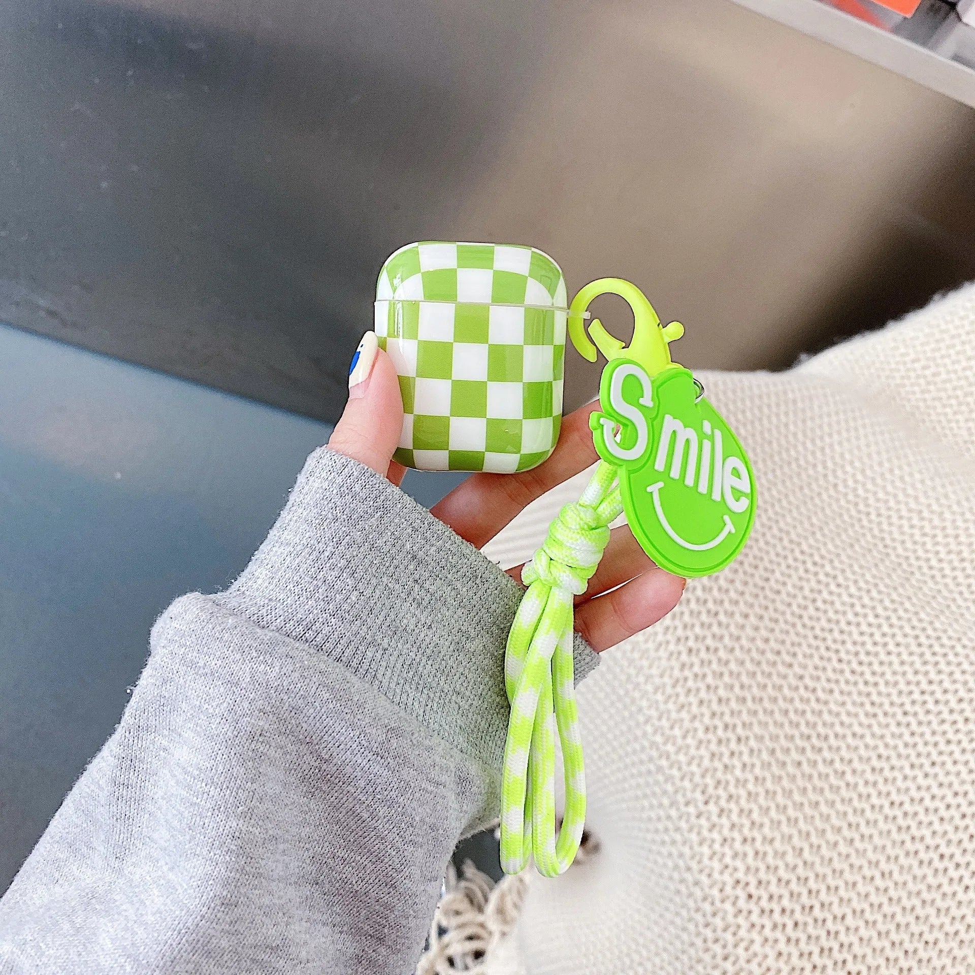 Black and green checkerboard patterned TPU protective case for Apple AirPods with optional lanyard and loop pendant attachments.