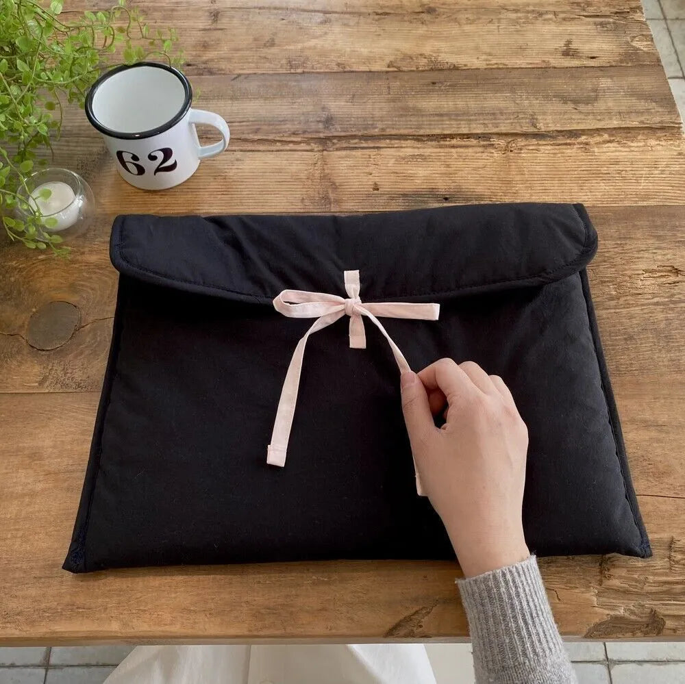 Black and white quilted women's laptop bag with a ballet bow, showing striped pattern and laptop compartment.