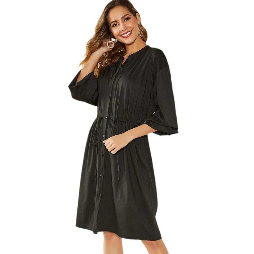 Black mid-length A-line dress with long sleeves and an elastic cinched waist with a loose belt.