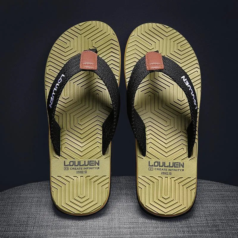 Men's black flip flops with a textured non-slip sole on a sandy beach background.