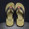 Men's black flip flops with a textured non-slip sole on a sandy beach background.