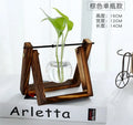 Glass tabletop plant with green artificial succulent in decorative pot on a wooden shelf