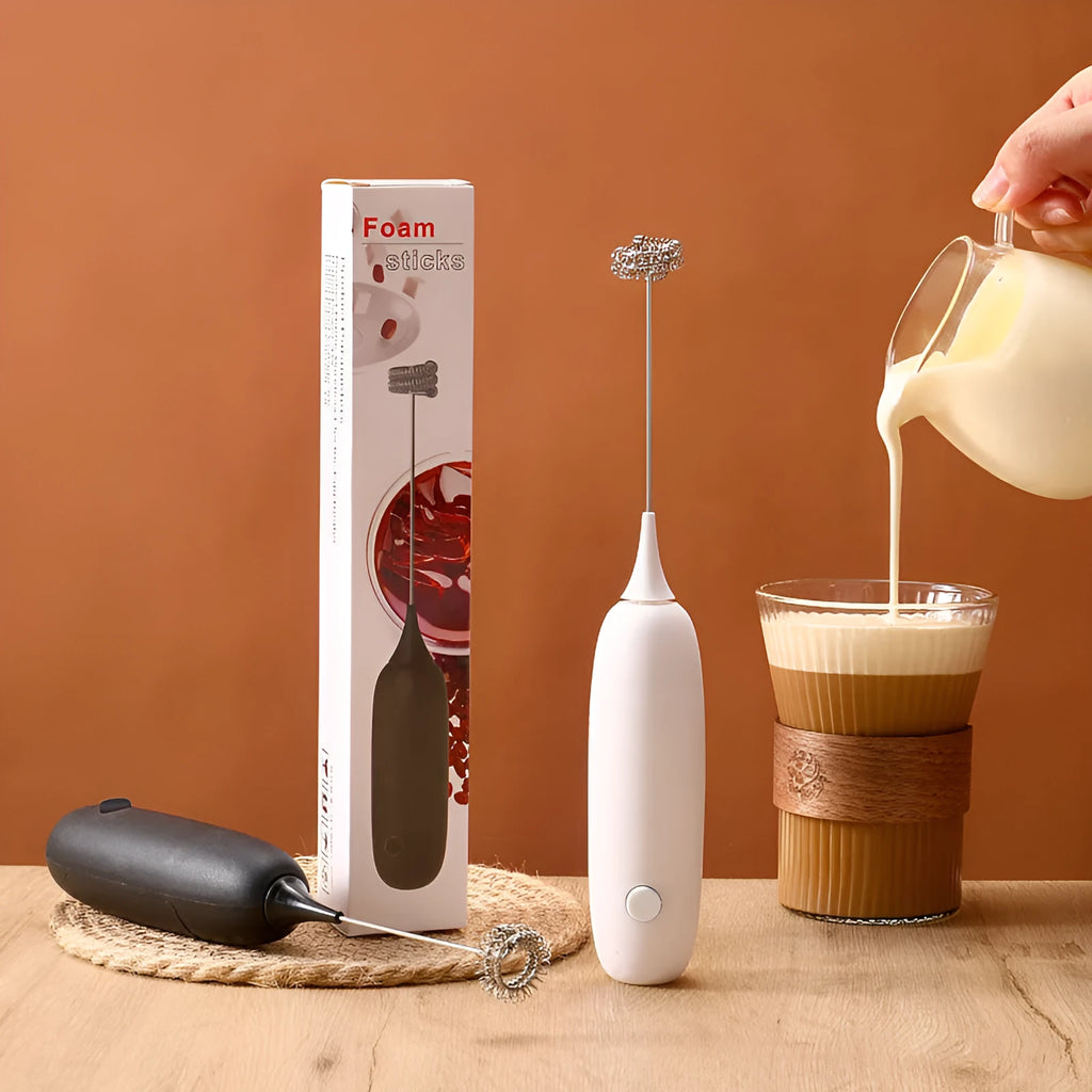 Black and white hand-held electric milk frother and blender on a kitchen counter.