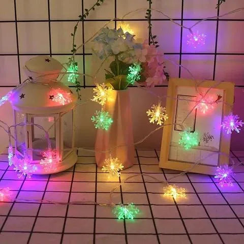 Battery powered LED snowflake string lights in warm white on a garden tree branch for Christmas decoration