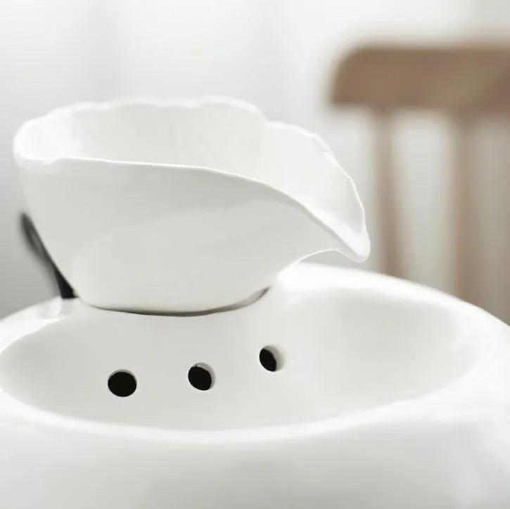 White ceramic automatic cat water dispenser with leaf design and US plug on a wooden floor