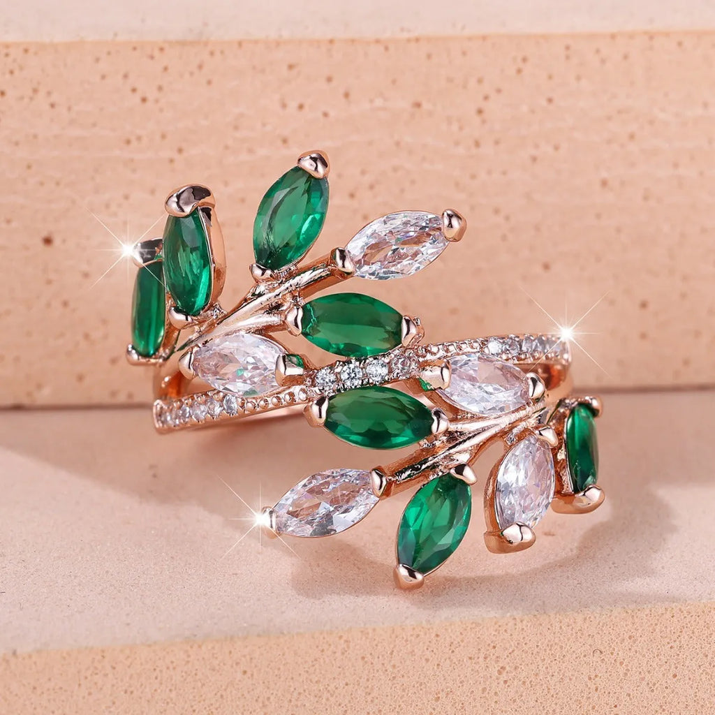 Adjustable open-ended copper ring with leaf design and central blue zircon stone on a finger.