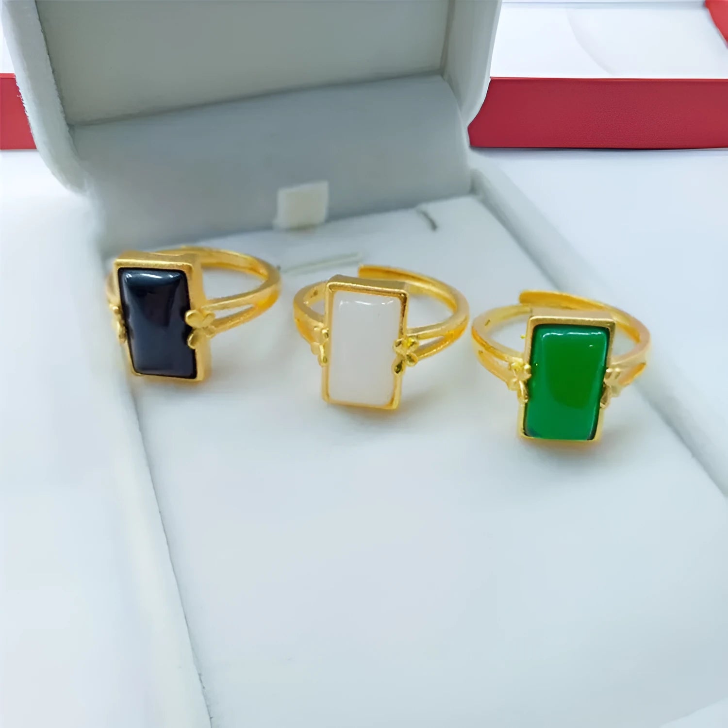 Adjustable brass gold-plated ring with a coloured gemstone inlay on a finger.
