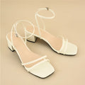 Beige women's stiletto sandals with chunky heel, square toe, and ankle buckle.
