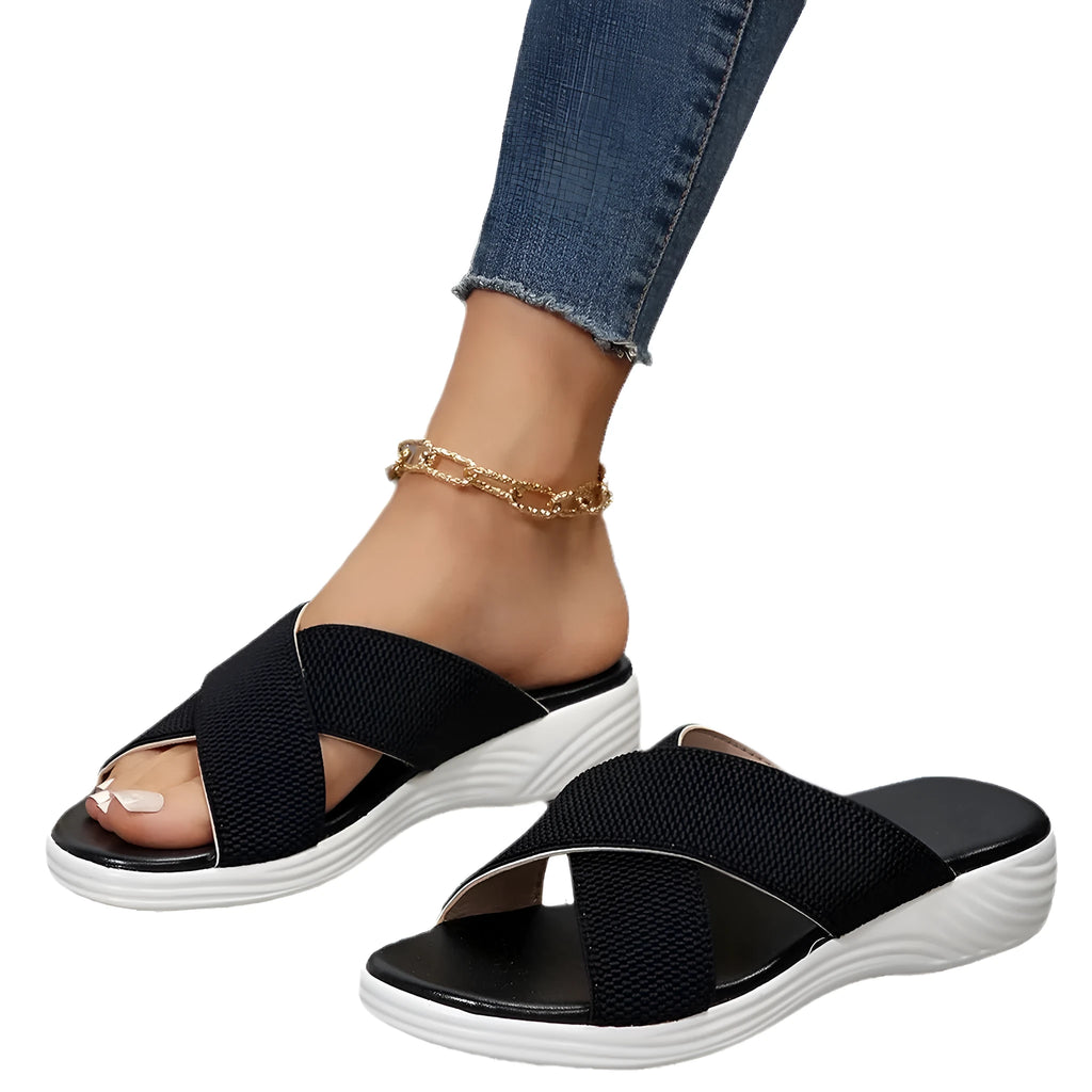 Black women's peep-toe slippers with a cross strap and thick flat rubber wedge sole.