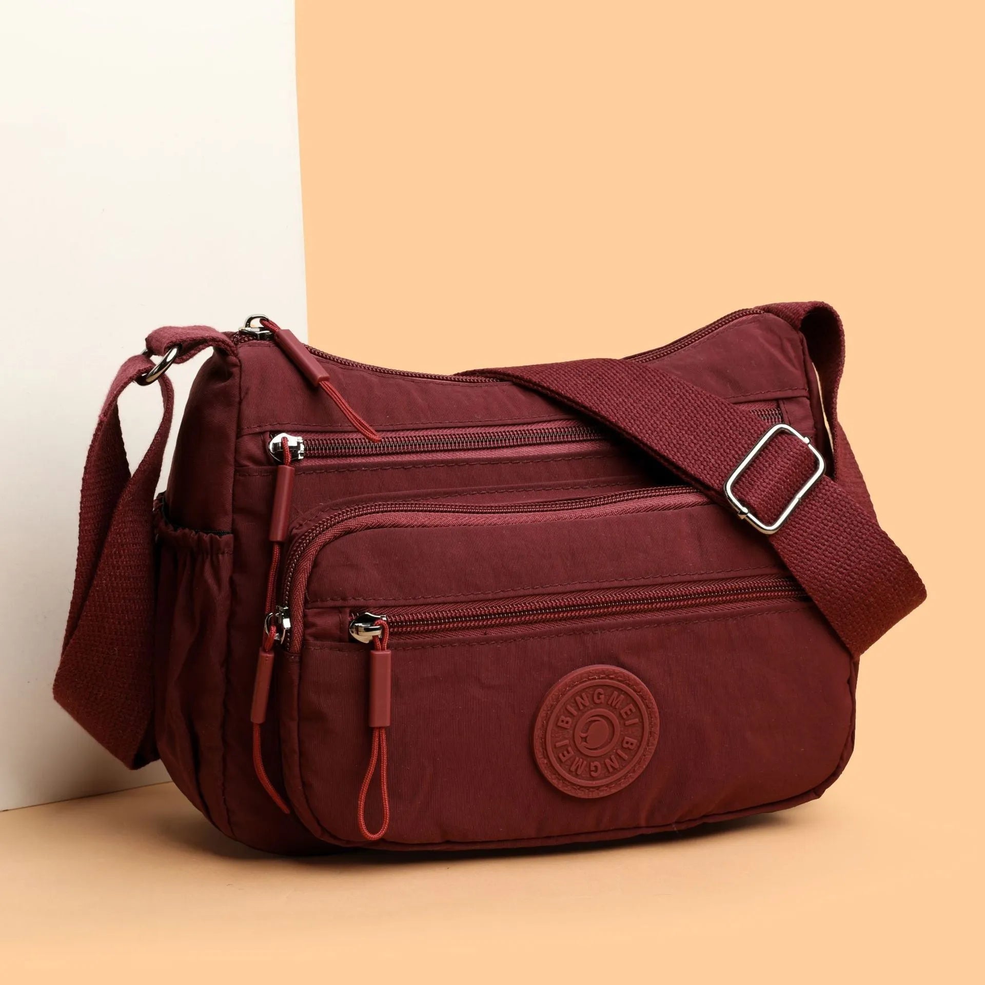 Soft water-repellent nylon crossbody bag with a three-dimensional front pocket and adjustable strap.