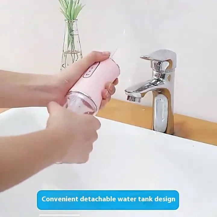 Pink portable electric water flosser with replaceable nozzles and large water tank on bathroom counter