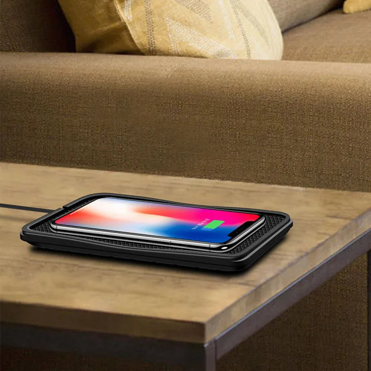Black wireless car charger with anti-slip base, shown on a car dashboard next to a mobile phone.