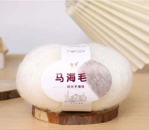 A ball of mohair yarn in a selected colour next to a hand-woven scarf example, showcasing the DIY kit.