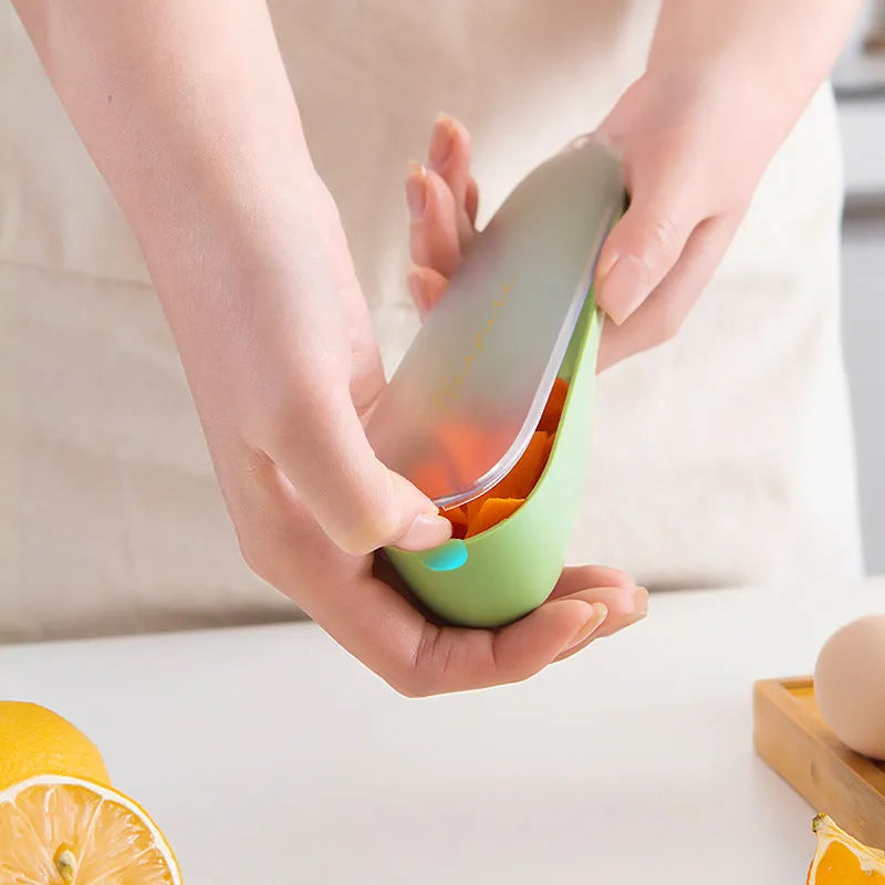Dark green kitchen peeler with a storage tube extended, showing the stainless steel blade and a hanging hole on the handle.