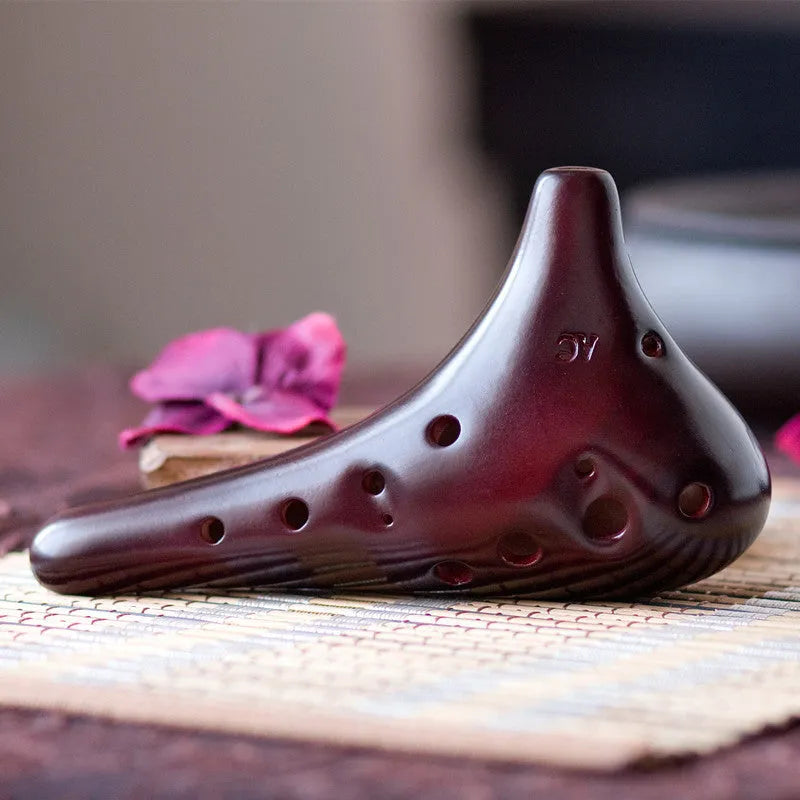 Smoked brown 12-hole dolomite ocarina, 14x8cm, midrange C, with raw lacquer surface.