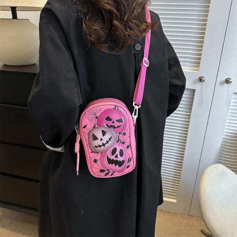 Black mini square crossbody bag with orange pumpkin, white ghost, and black bat graffiti print on the front.
