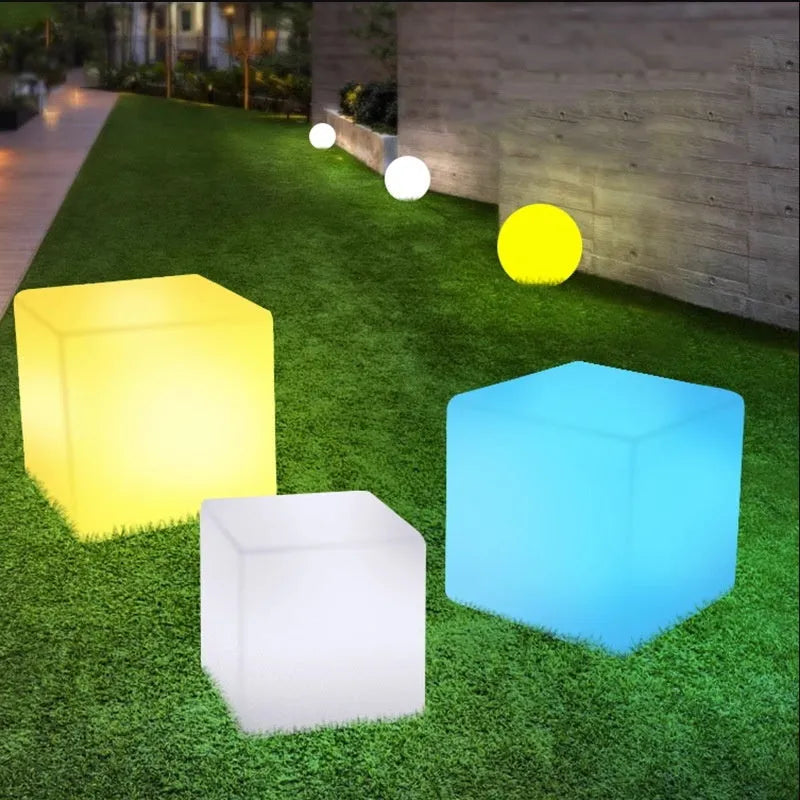 A modern square white LED cube light functioning as a waterproof stool for outdoor gardens.