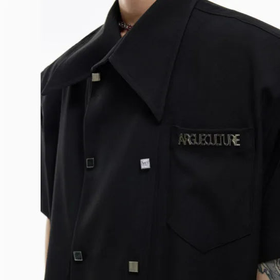 A man's loose-fitting casual short-sleeved shirt in blue with metal buttons and contrast panel detail.