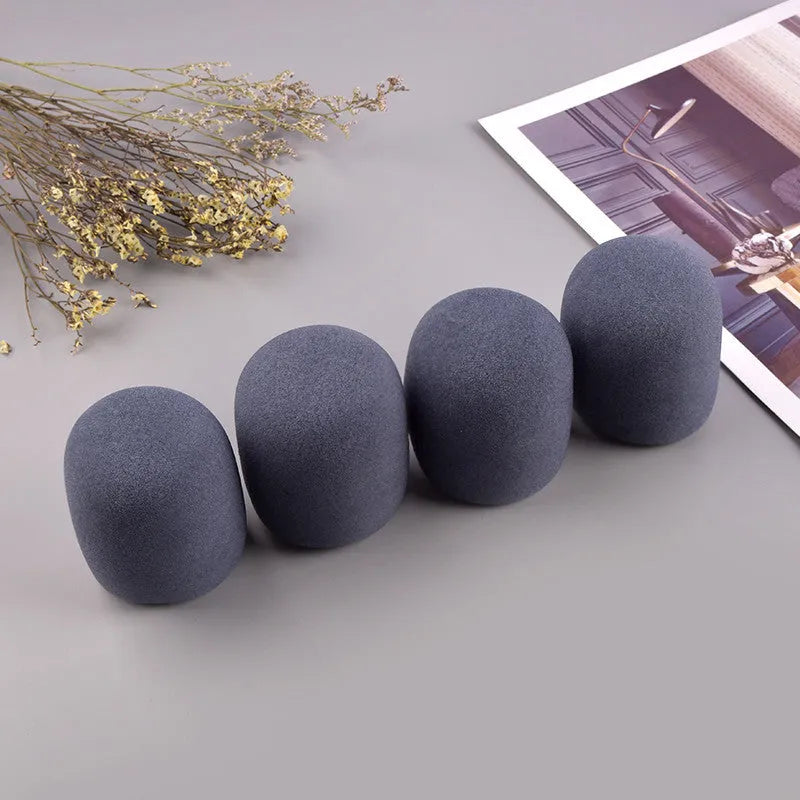 Four multicolored foam microphone windshields for handheld stage microphones on a grey background.