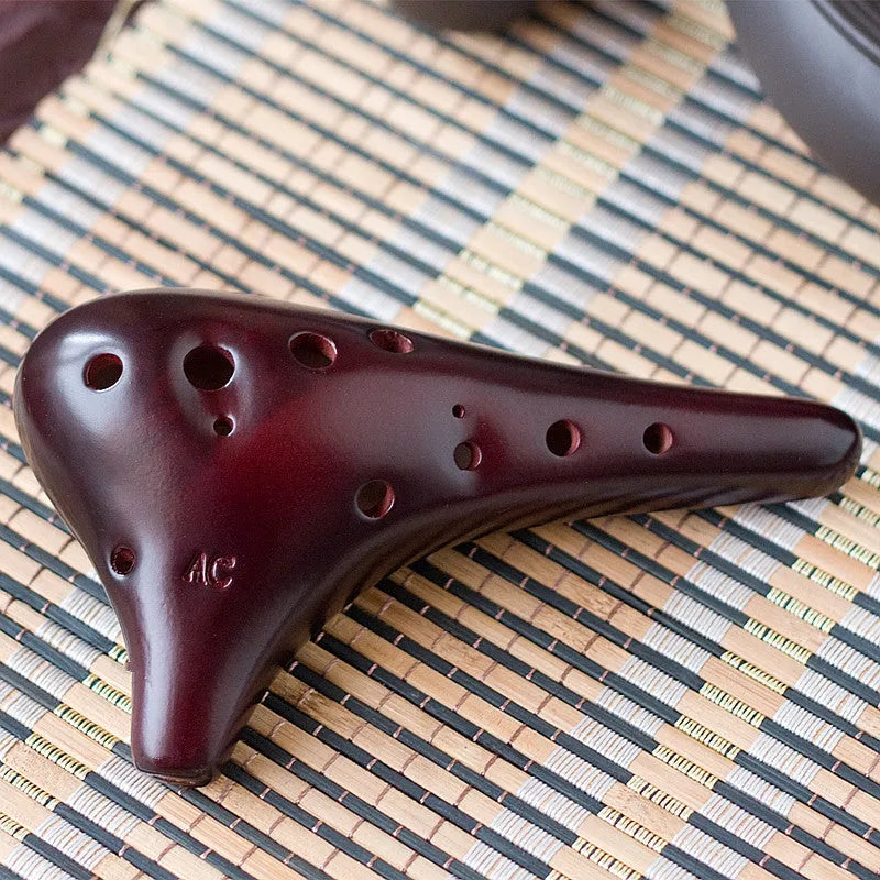 Smoked brown 12-hole dolomite ocarina, 14x8cm, midrange C, with raw lacquer surface.