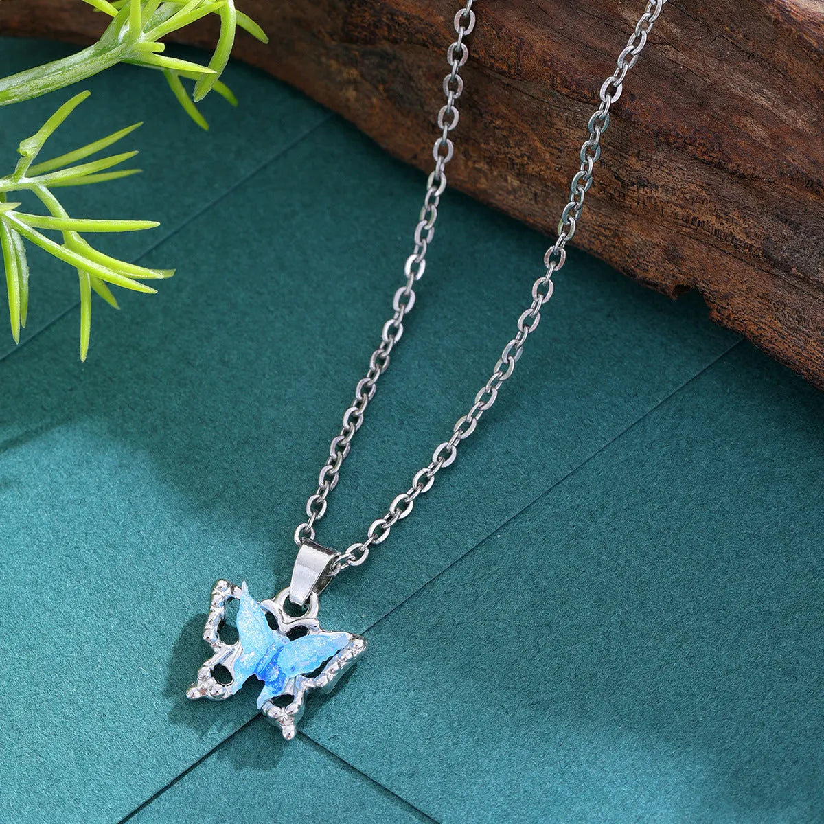 Blue three-dimensional butterfly pendant necklace for women on a light background