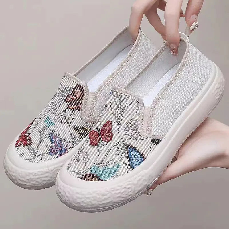 Women's black and white canvas slip-on shoes with round toe and decorative stitching.