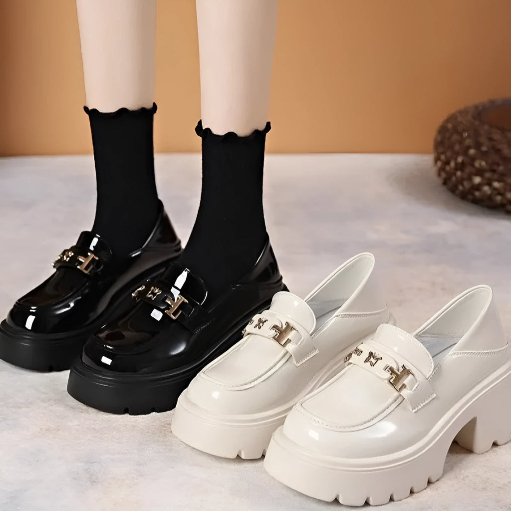 Black slip-on leather shoes with a chunky square heel and a skull pattern on the upper.