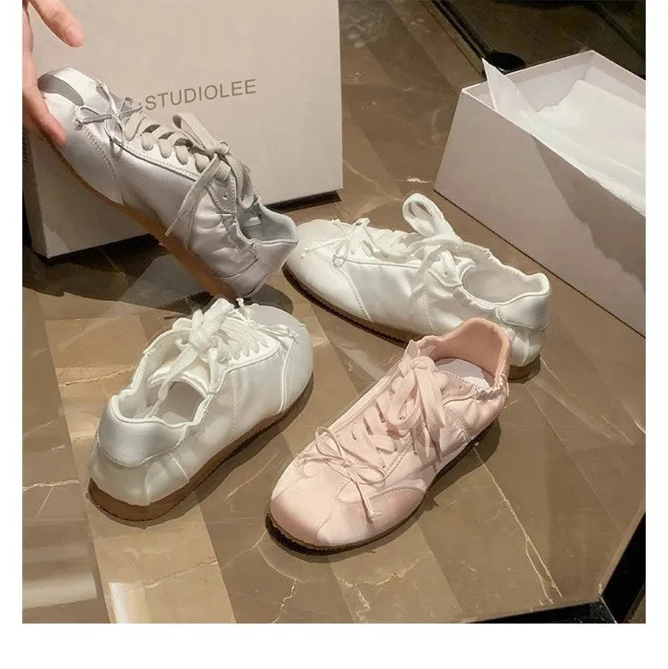 Women's silver grey satin ballet flat shoes with front lace-up design and round toe.