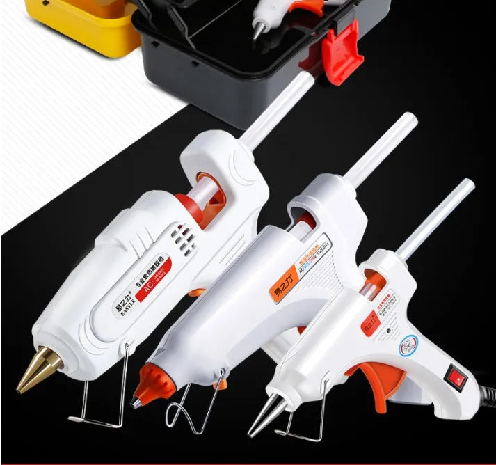 White electric hot glue gun with a metal stand and anti-heat blanket on a table.