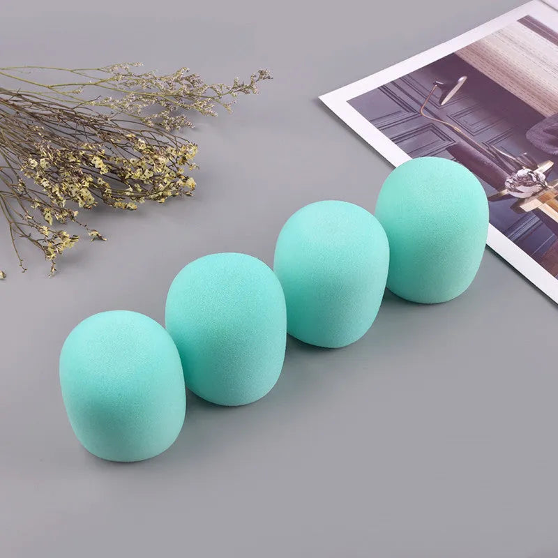 Four multicolored foam microphone windshields for handheld stage microphones on a grey background.