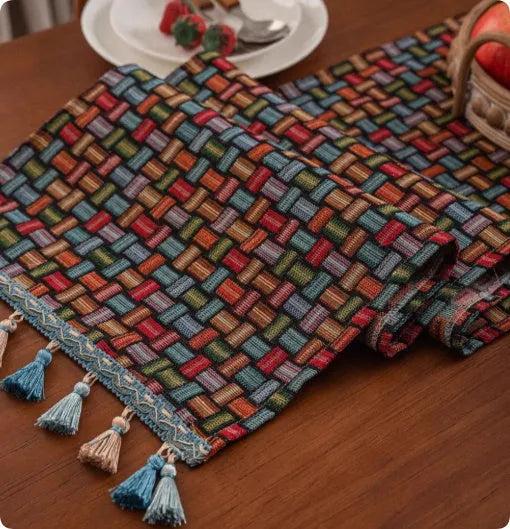 Country European retro style table flag with handwoven tassels in blue ginkgo leaf pattern lying on a wooden table.