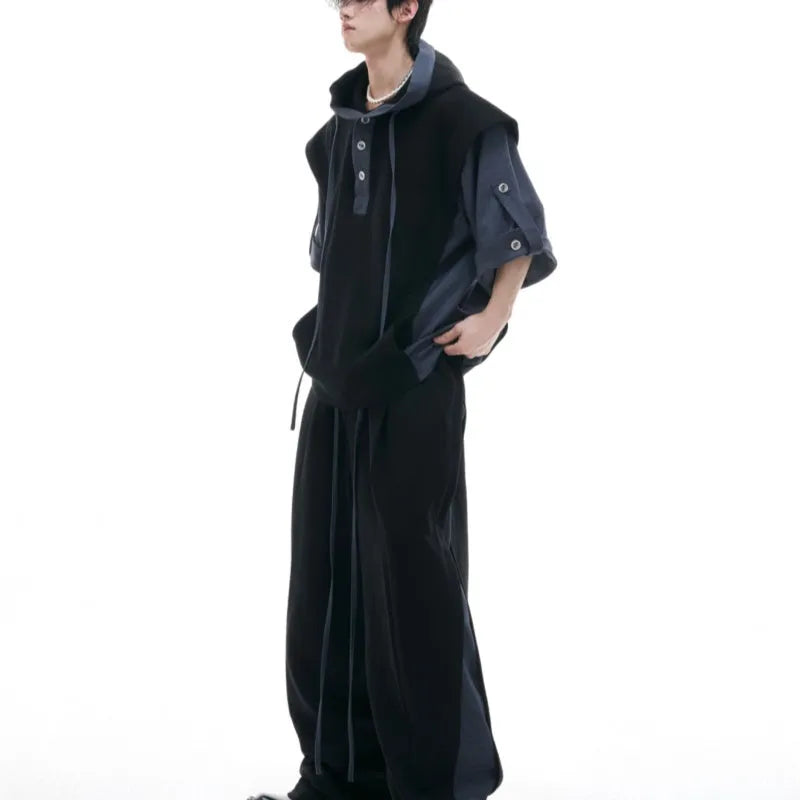 Man wearing a black hooded short sleeve sports jacket with textured stitching and matching full-length trousers.