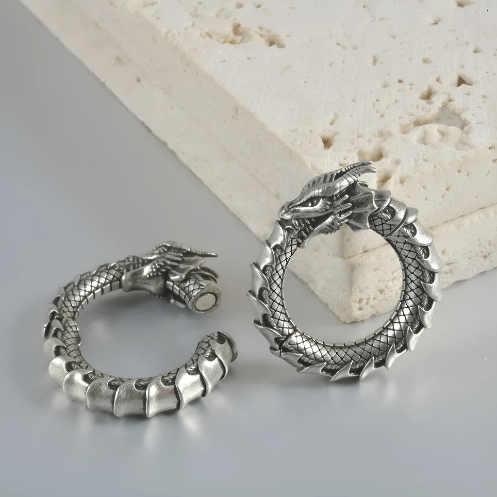Pair of large antique silver dragon-shaped hollow-out earrings with geometric design on a plain background.