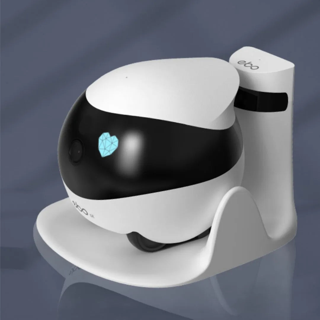 White cube-shaped mobile robot camera with camera lens on a flat surface next to its docking station.
