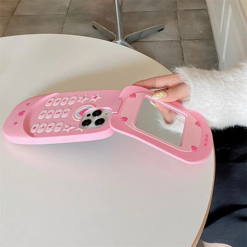 Pink silicone flip phone case for iPhone with a built-in compact mirror on the front.