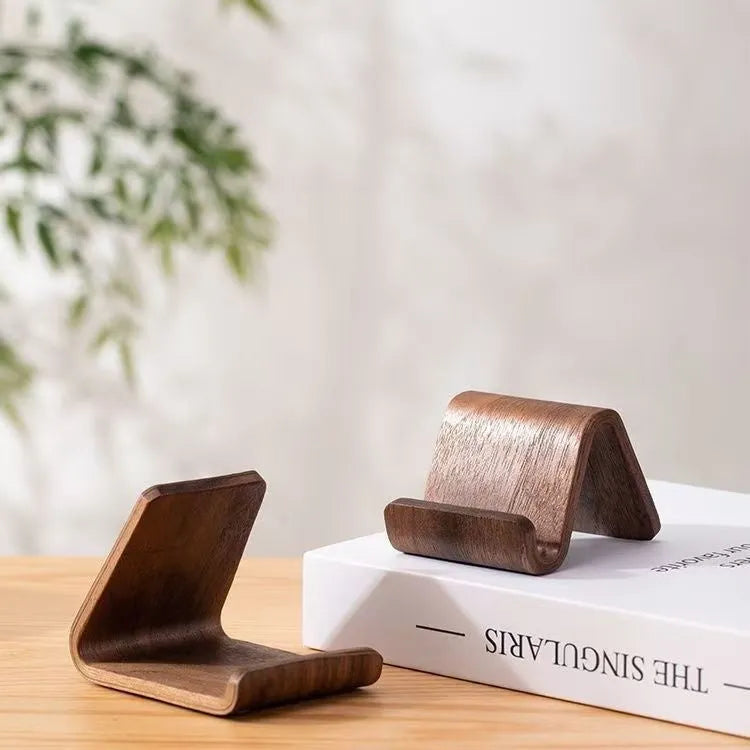 Walnut wood mobile phone bracket on a desk holding a smartphone upright for handsfree viewing